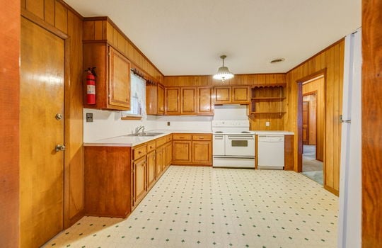 kitchen, vinyl flooring, paneling walls, wood cabinets, countertops, oven/range, dishwasher, refrigerator, sink, exterior door
