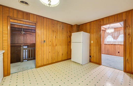 kitchen, vinyl flooring, paneling walls, refrigerator, door to living room, door to dining space
