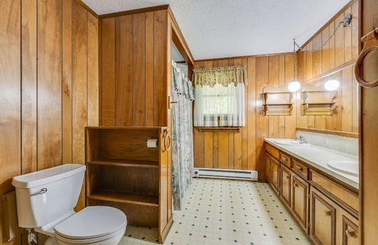 bathroom, double vanity, vinyl flooring, shelving, toilet, sinks, shower/tub, paneling walls