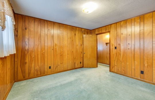 bedroom, carpet, paneling walls, door to hallway