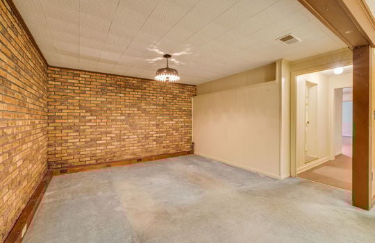 lower level living area, ceiling tiles, brick feature wall, paneling walls, doorway