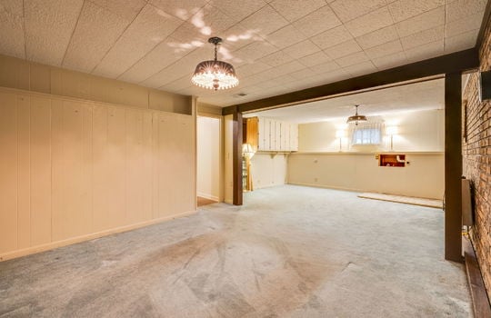 lower level living area, ceiling tiles, brick feature wall, doorway, built-in cabinetry, washer/dryer hookups