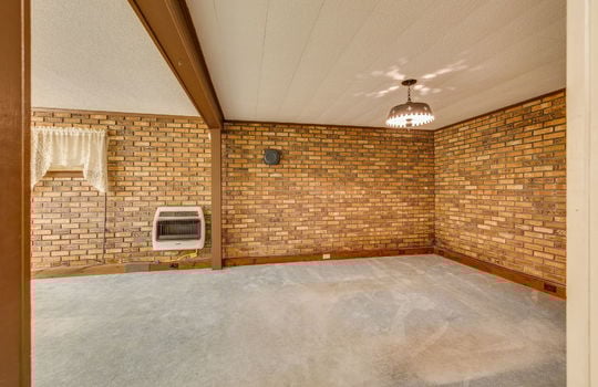 lower level living area, carpet, window, brick feature wall, ceiling tiles