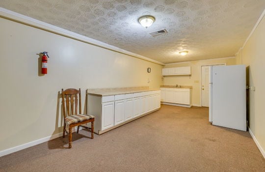 lower level kitchen, cabinets, countertops, carpet, sink, refrigerator, exterior door