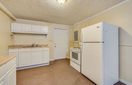 lower level kitchen area, cabinets, countertops, sink, exterior door, oven/range, refrigerator, carpet