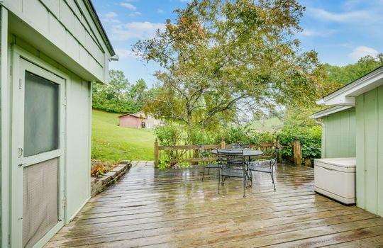rear patio, deck boards, exterior door, deck railing, trees/landscaping, workshop