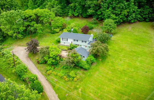 aerial view of home, driveway, landscaping, front yard, back yard, trees, workshop, split level home, wood siding, brick, front door