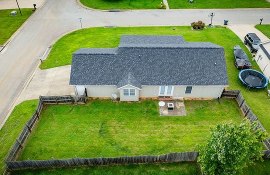 aerial view of back yard, back of home, vinyl siding, fencing, patio, roof, driveway
