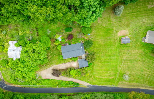 aerial view of home, driveway, landscaping, front yard, back yard, trees, workshop, split level home, wood siding, brick, front door, neighboring homes
