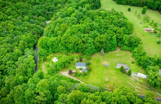 aerial view of home, driveway, landscaping, front yard, back yard, trees, workshop, split level home, wood siding, brick, front door, trees, neighboring homes