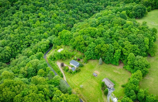 aerial view of home, driveway, landscaping, front yard, back yard, trees, workshop, split level home, wood siding, brick, front door, trees, neighboring homes