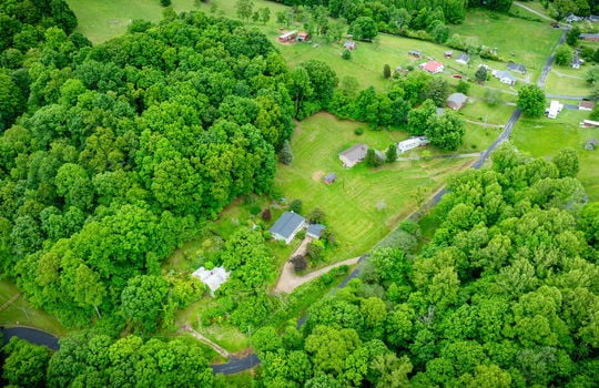 aerial view of home, driveway, landscaping, front yard, back yard, trees, workshop, split level home, trees, neighboring homes