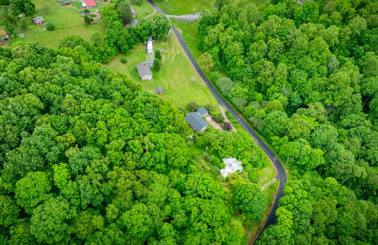 aerial view of home, driveway, landscaping, front yard, back yard, trees, workshop, split level home, trees, neighboring homes, road