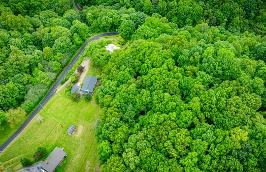aerial view of home, driveway, landscaping, front yard, back yard, trees, workshop, split level home, trees, neighboring homes, road