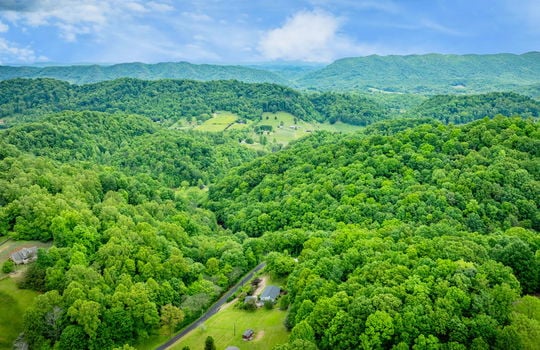 aerial view of home, driveway, landscaping, front yard, back yard, trees, workshop, split level home, trees, neighboring homes, road, mountains