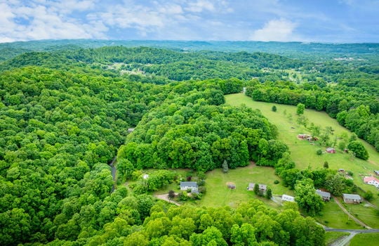 aerial view of home, driveway, landscaping, front yard, back yard, trees, workshop, split level home, trees, neighboring homes, road, mountains