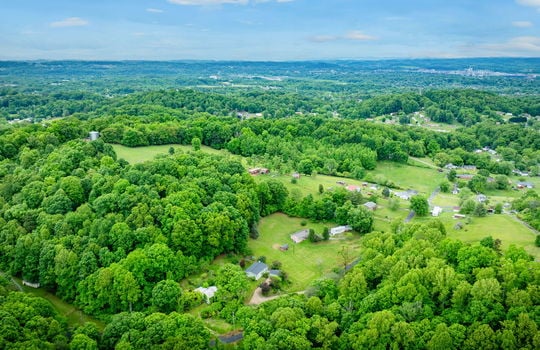 aerial view of home, driveway, landscaping, front yard, back yard, trees, workshop, split level home, trees, neighboring homes, road, mountains