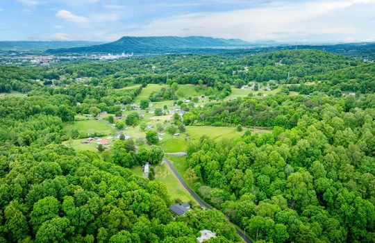 aerial view of home, driveway, landscaping, front yard, back yard, trees, workshop, split level home, trees, neighboring homes, road, mountains