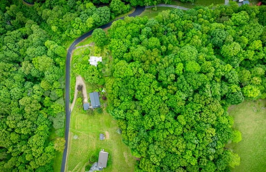 aerial view of home, driveway, landscaping, front yard, back yard, trees, workshop, split level home, trees, neighboring homes, road, mountains