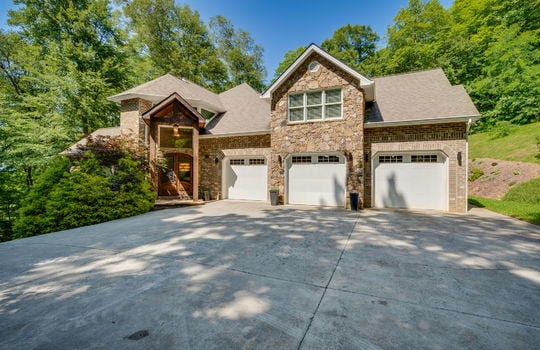 two story traditional home, driveway, three car garage, brick and stone exterior, roof, freont door, trees