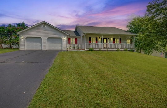 twilight photo, ranch style home, vinyl siding, covered front porch, front door, two car attached garage, driveway