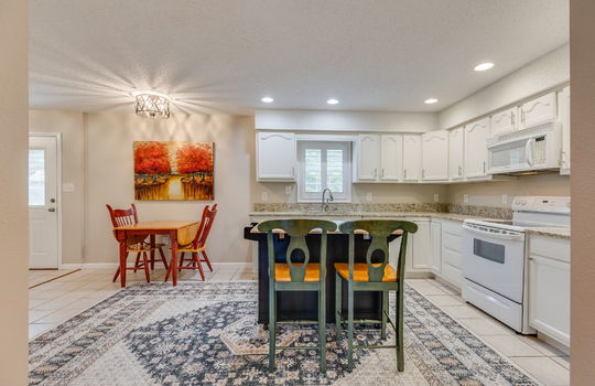 kitchen, tile flooring, granite countertops, white cabinets, built in microwave, oven/range, sink, window above sink, back exterior door