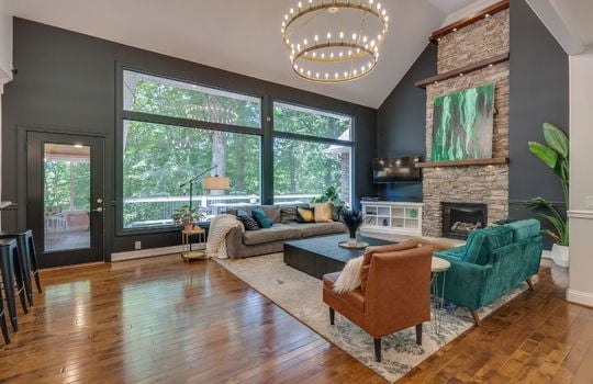 living room, large picture windows, vaulted ceilings, stone fireplace, hardwood flooring, door to sunroom & back deck