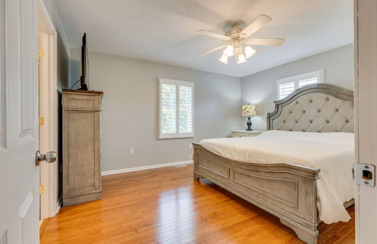 primary bedroom, hardwood flooring, ceiling fan, windows, door to primary ensuite
