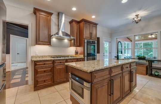 kitchen, tile flooring, cabinets, granite countertops, double wall oven, refrigerator, cooktop, sink, kitchen island, sink in island, kitchen sink, granite countertops, recessed lighting, view into sunroom