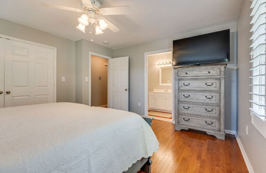 primary bedroom, ceiling fan, window, closet, door to primary bathroom, hardwood flooring
