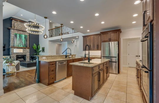 kitchen, tile flooring, cabinets, granite countertops, double wall oven, refrigerator, cooktop, sink, kitchen island, sink in island, kitchen sink, granite countertops, recessed lighting, dishwasher, view into living room
