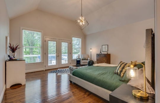 primary bedroom, back deck access doors, vaulted ceilings, hardwood flooring, windows