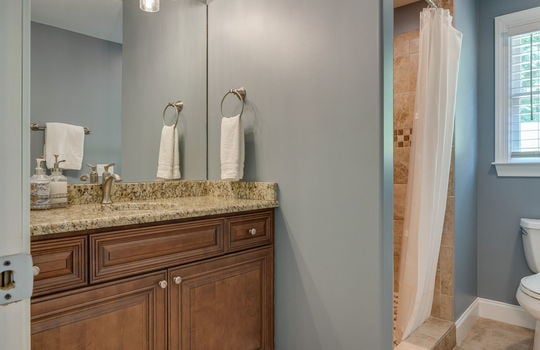 bathroom, granite countertop, tile flooring, tile shower, toilet