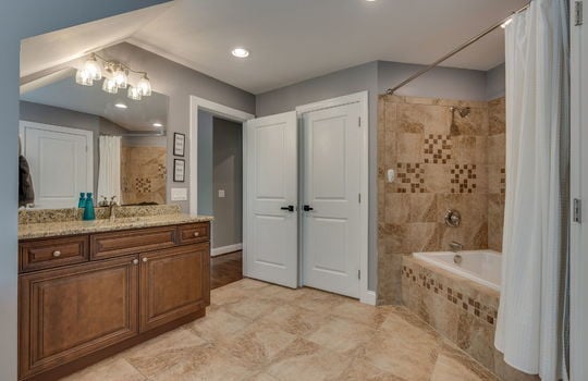 bathroom, tile flooring, shower/tub, tile shower wall, sink, granite countertop