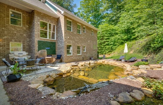 back patio, rock pond, rock waterfall, brick home exterior, windows, back yard