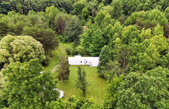aerial view of back of property, back yard, storage shed, trees, gravel driveway, singlewide, back deck