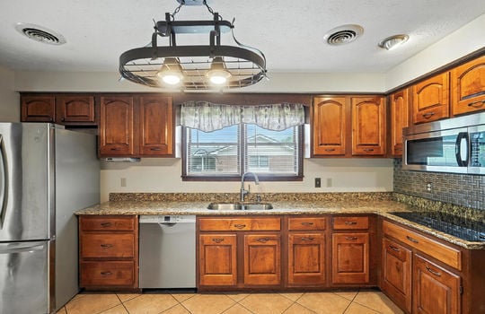 kitchen, tile flooring, countertops, stainless appliances, microwave, dishwasher, refrigerator, cooktop, cabinets, sink, pot rack light