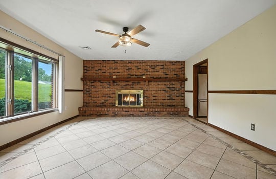 den, tile flooring, brick fireplace, gas fireplace, wood trim, ceiling fan