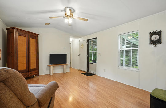 living room, front door, screen door, window, laminate flooring, hallway to second bedroom, ceiling fan