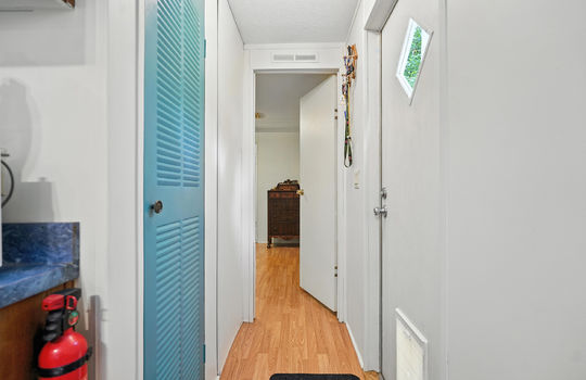 hallway, utility closet, exterior door, door to primary bedroom, laminate flooring