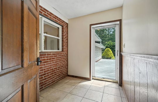 foyer, tile flooring, brick feature wall, window, exterior door