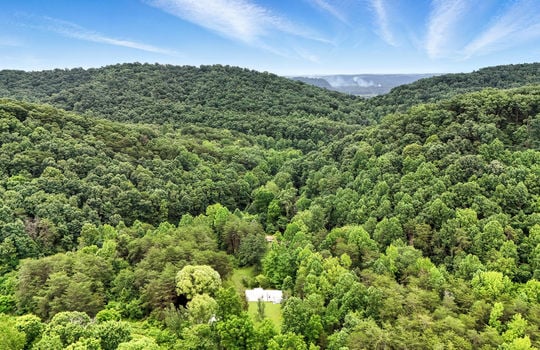 aerial view of property, singlewide, metal roof, back deck, covered front porch, front yard, back yard, trees, carport, mountain views