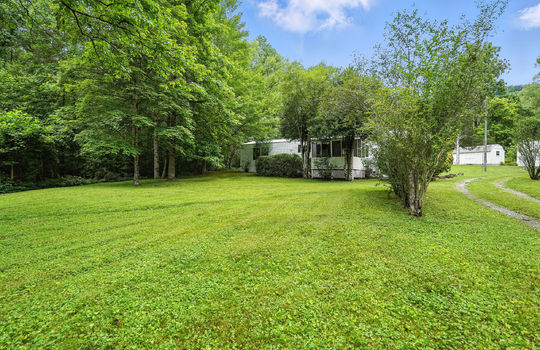 front yard, gravel driveway, trees, landscaping, singlewide, storage shed