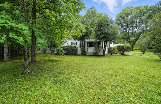 front yard, trees, landscaping, gravel driveway, singlewide, vinyl siding, covered front porch