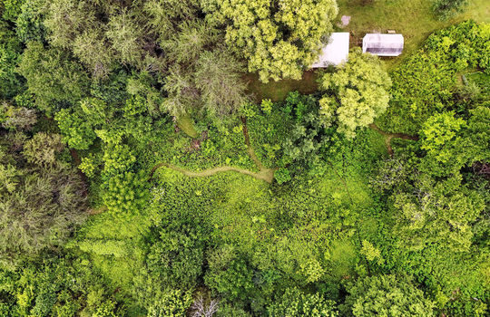 aerial view of property, singlewide, metal roof, back deck, covered front porch, front yard, back yard, trees, carport, walking path