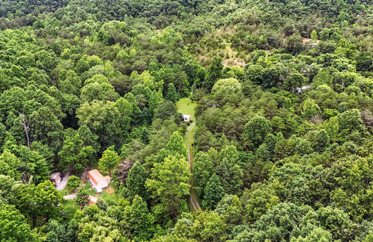 aerial view of property, trees, gravel driveway, neighboring homes