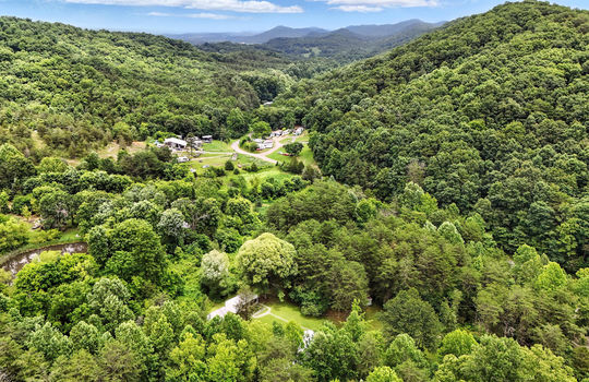aerial view of property and neighboring homes, creek, mountain views