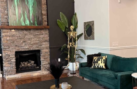 golden fake skeleton in living room, living room, hardwood flooring, chandelier, stone fireplace, vaulted ceiling