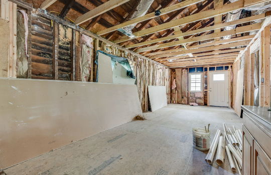 demoed living room, subflooring, wood framing for walls and ceiling, front door, window, fixer upper
