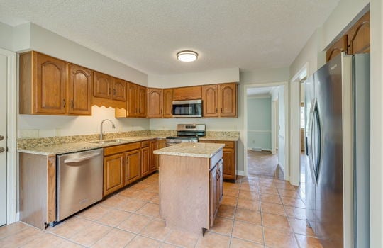 kitchen, cabinets, granite countertops, refrigerator, stove/oven, built-in microwave, dishwasher, sink, tile flooring